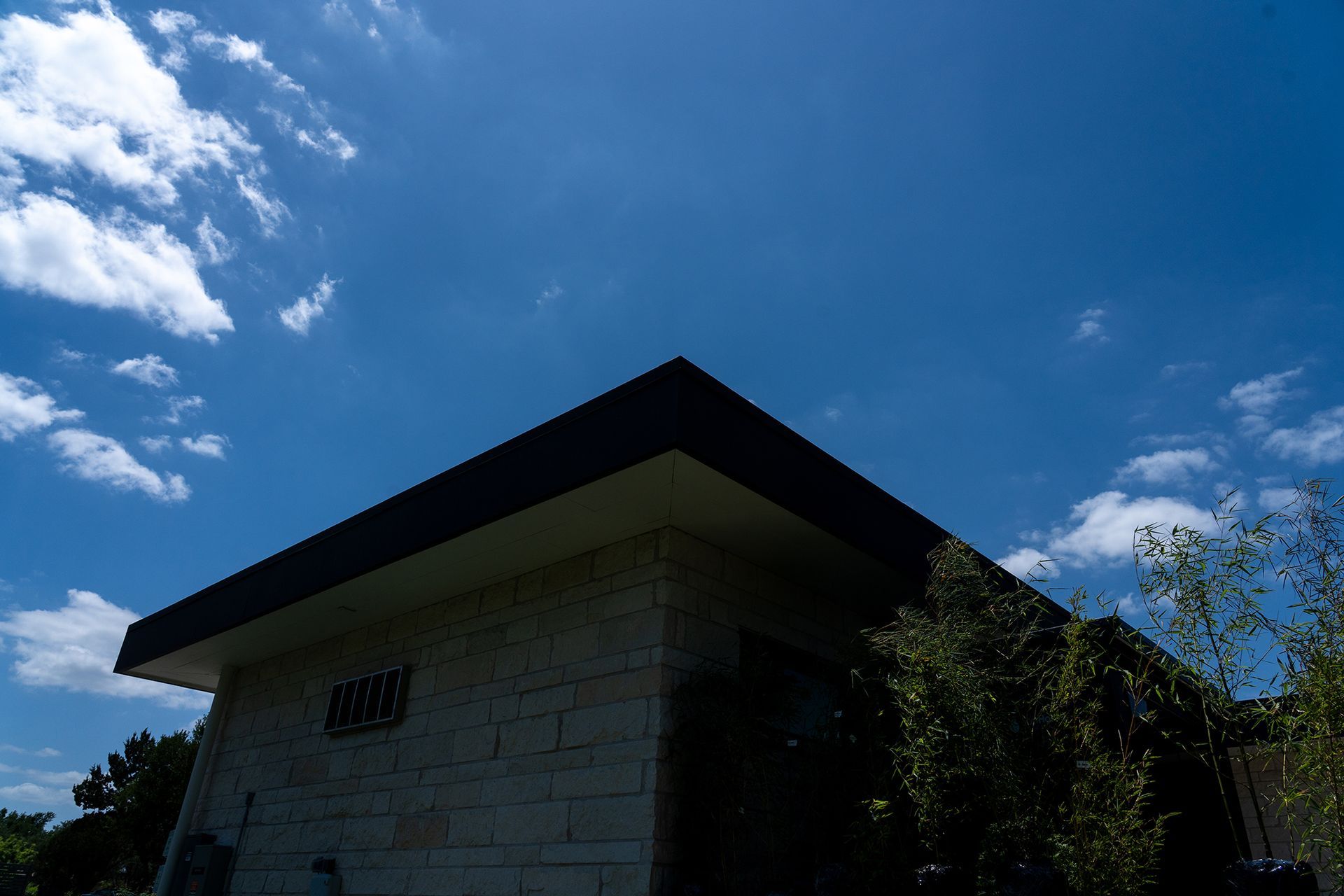 Blue sky above a light-colored building with a dark roof.
