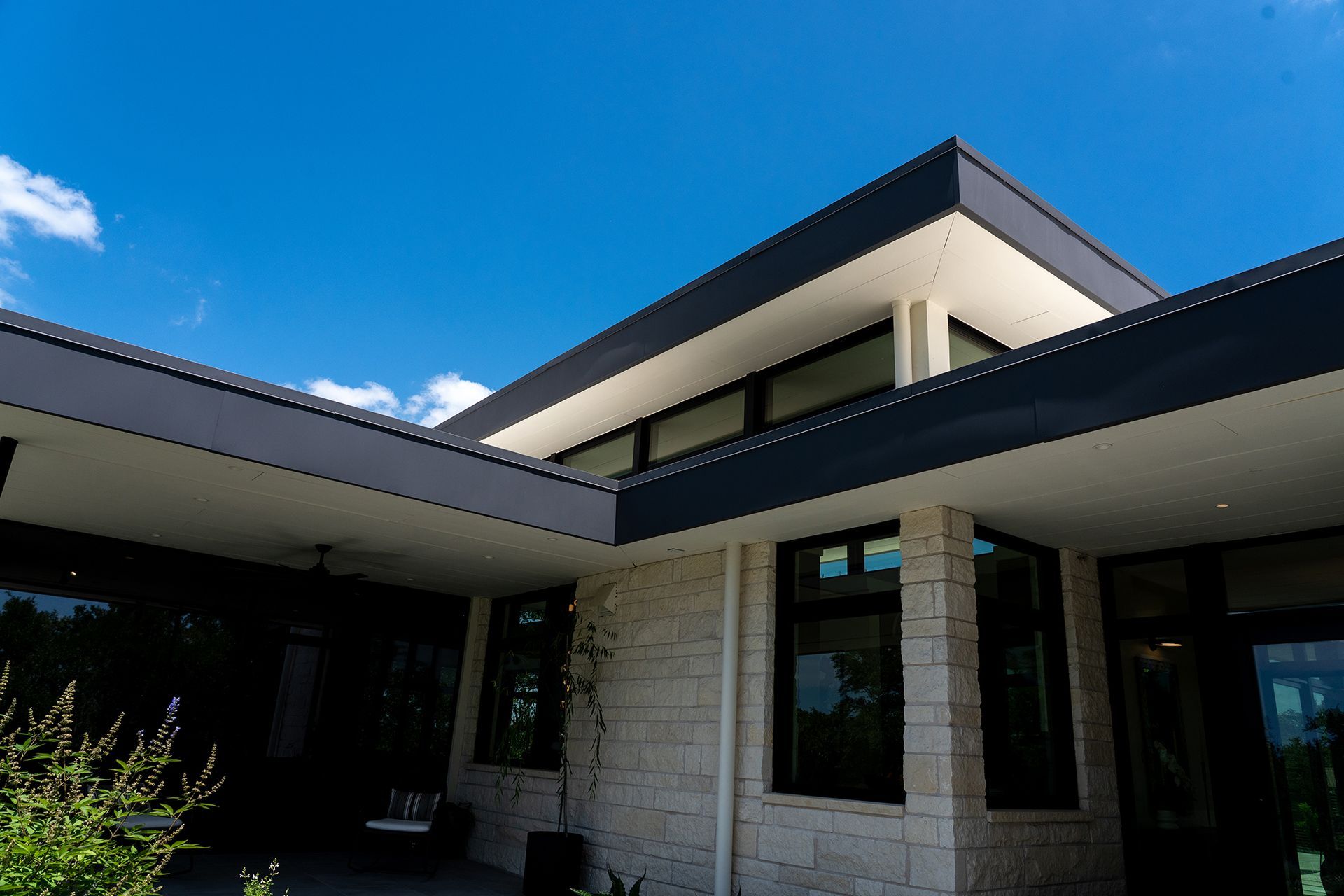 Modern home exterior with gray roof, white walls, and blue sky.