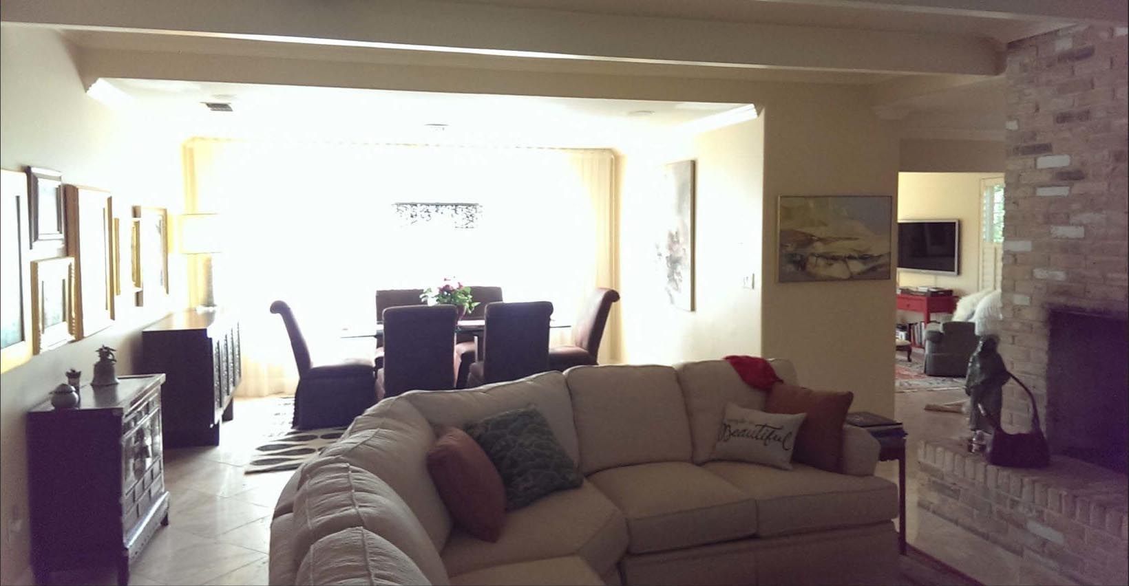 Beige living room with a sectional sofa, leading to a dining area with a table and chairs.
