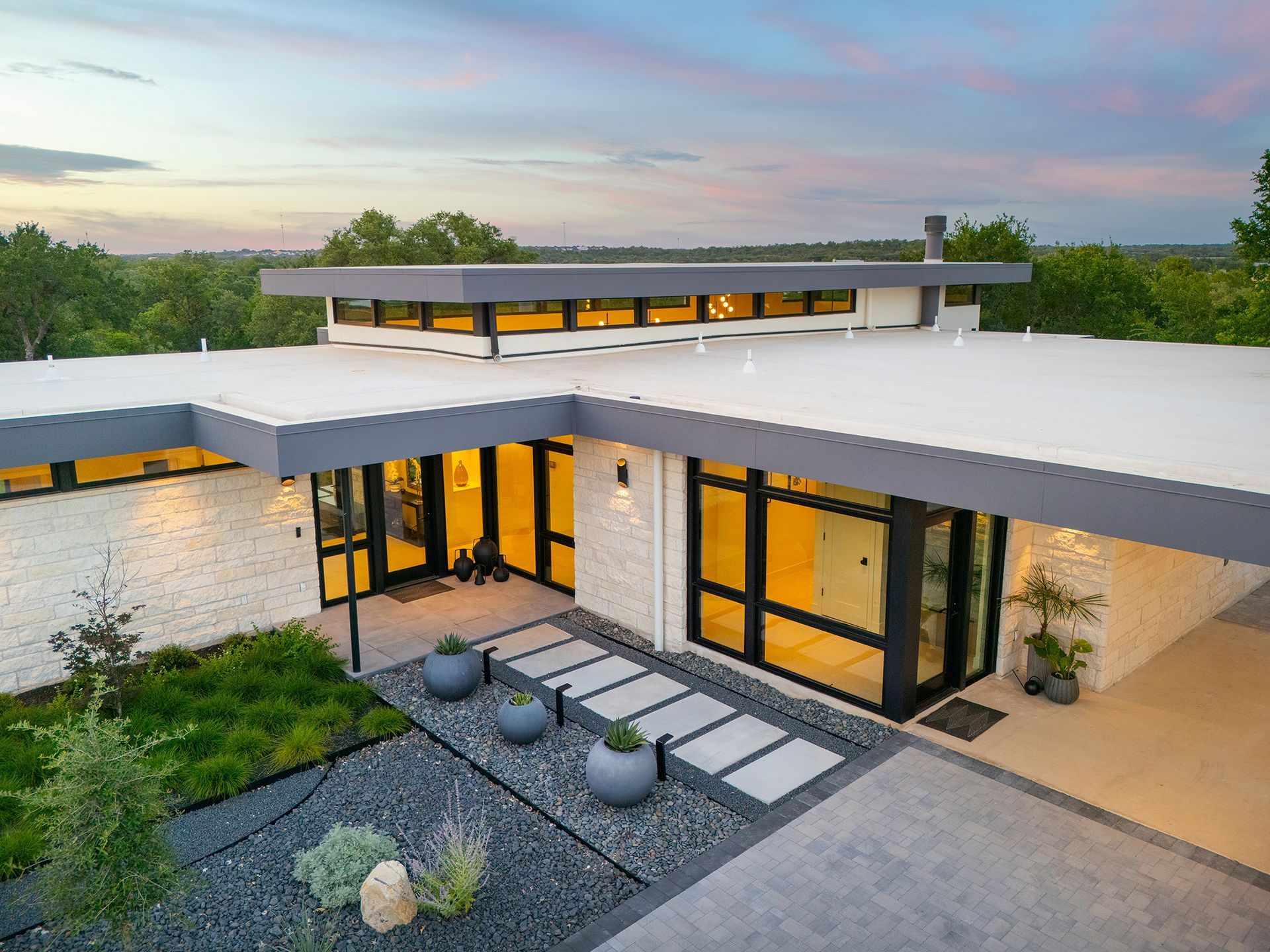 Modern home exterior with gray roof and trim, light brick facade, and landscaped yard.
