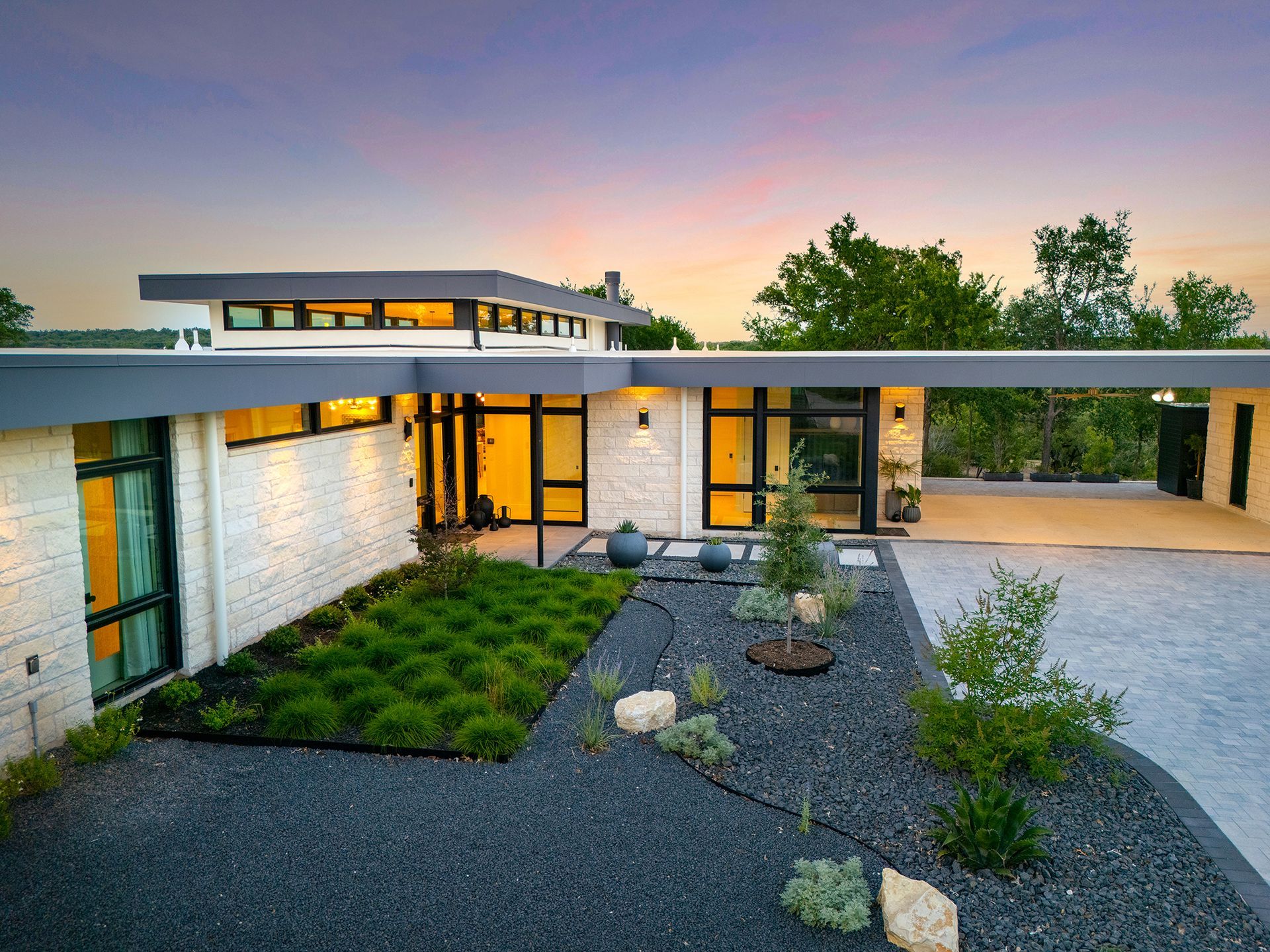 Modern home with white brick facade, black trim, and landscaped yard.
