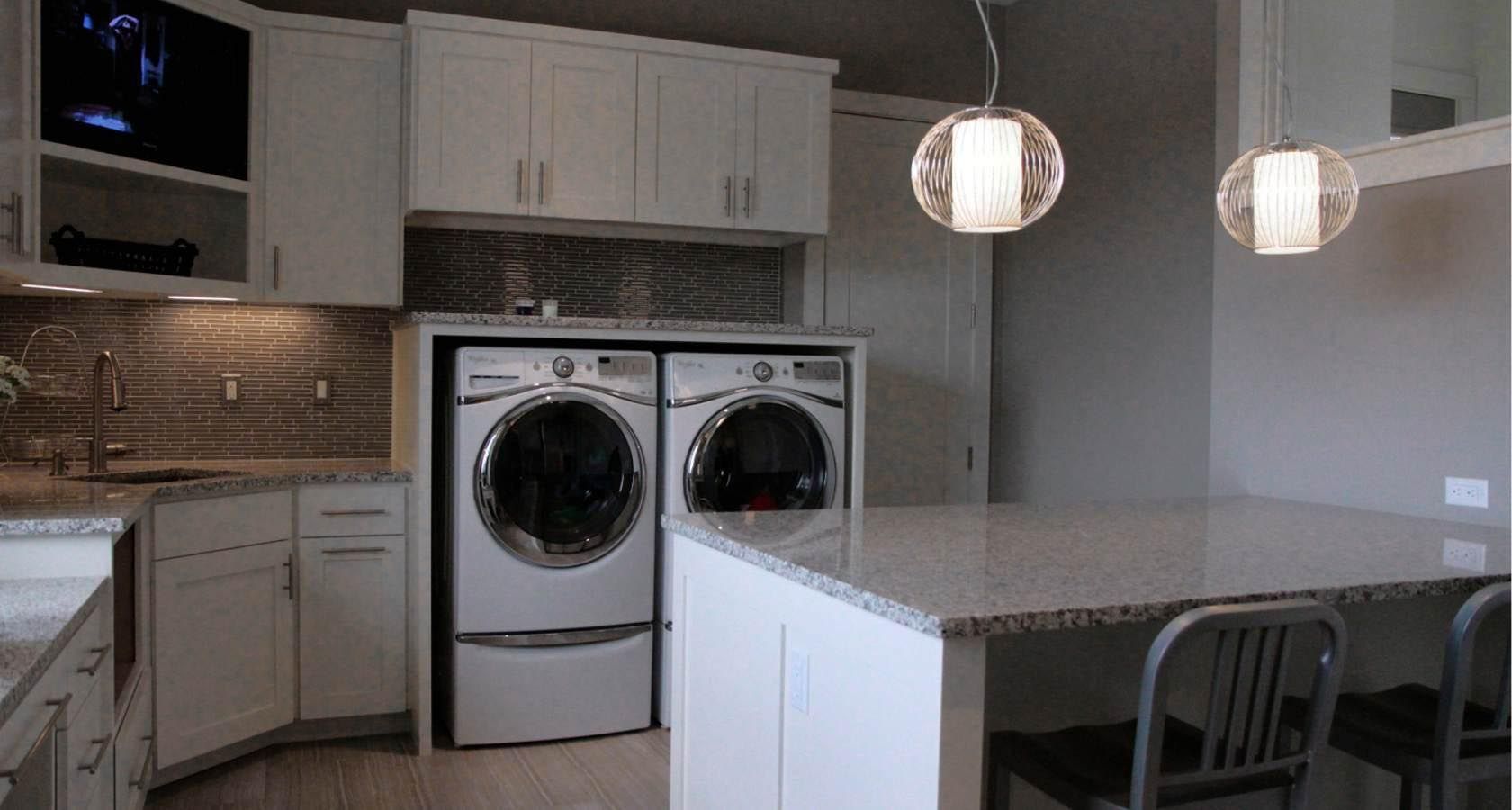 Laundry room with white cabinets, granite countertops, and washer/dryer.