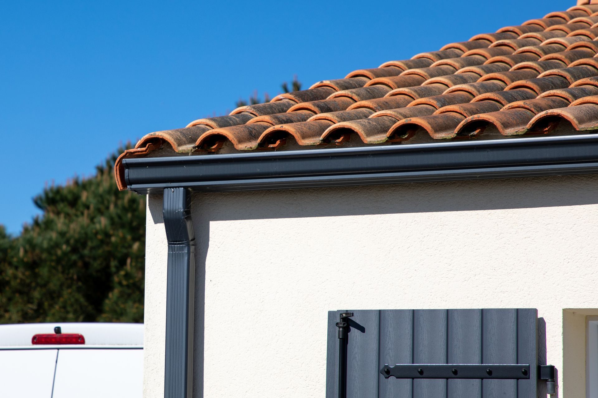 A house with a tiled roof and a gutter on the side of it.