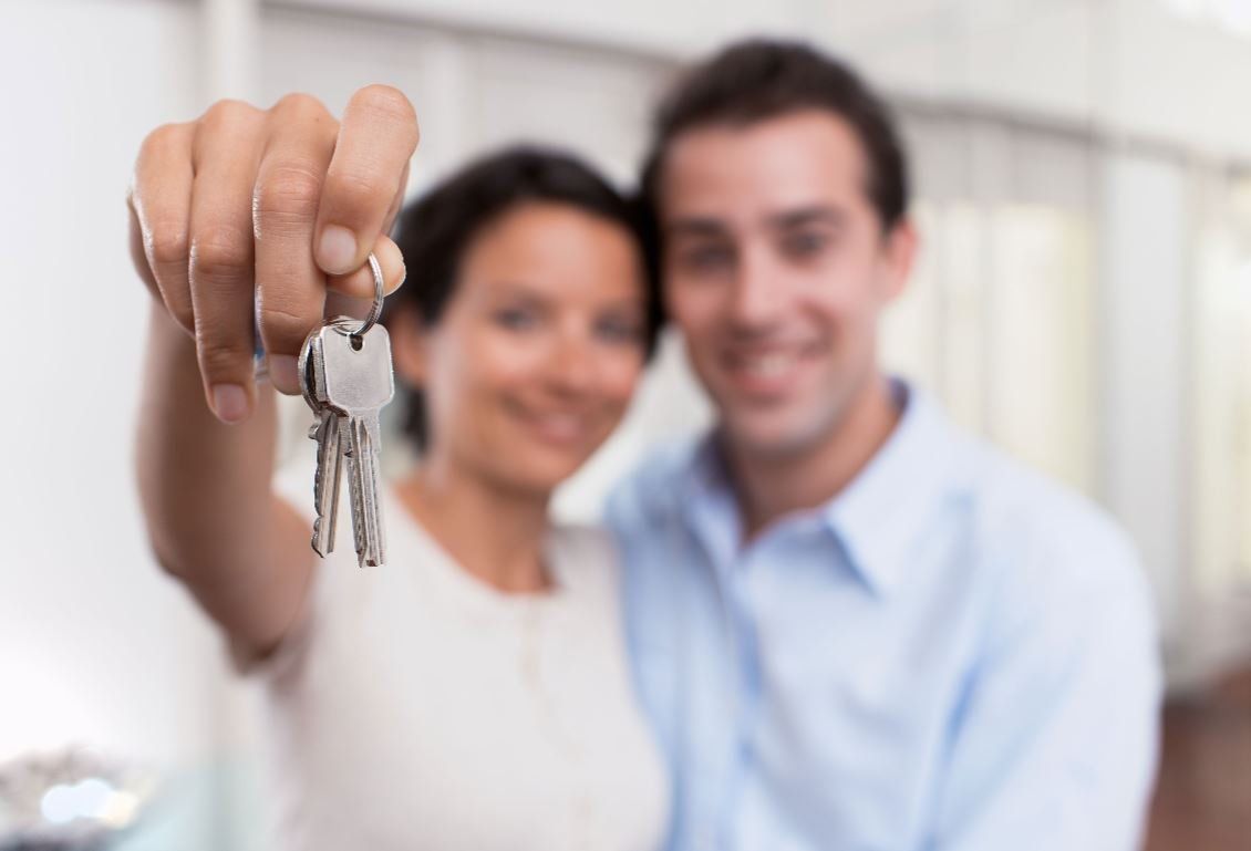 Couple showing keys to house