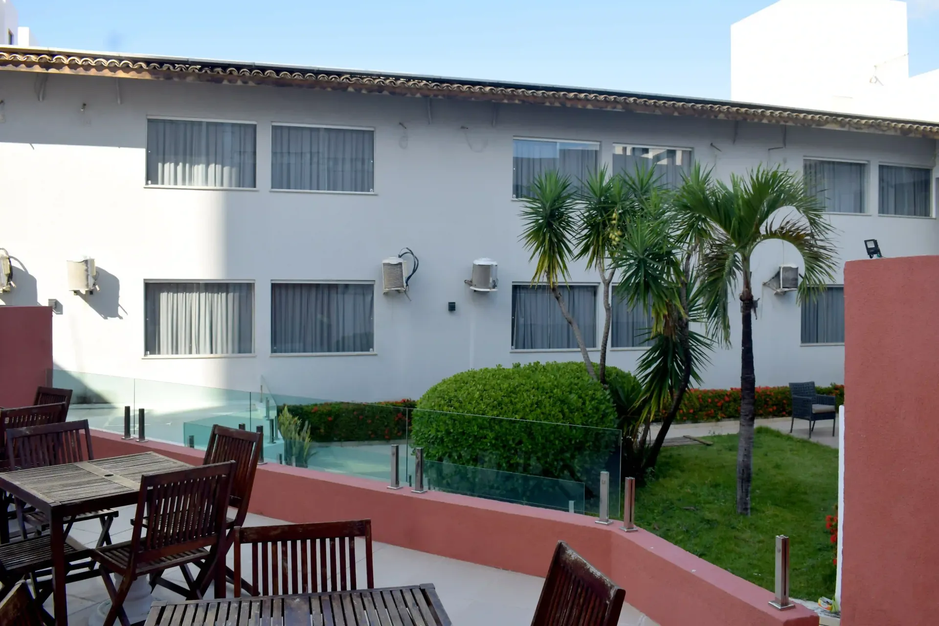 Um prédio branco com uma piscina na frente- Alto da Praia Hotel