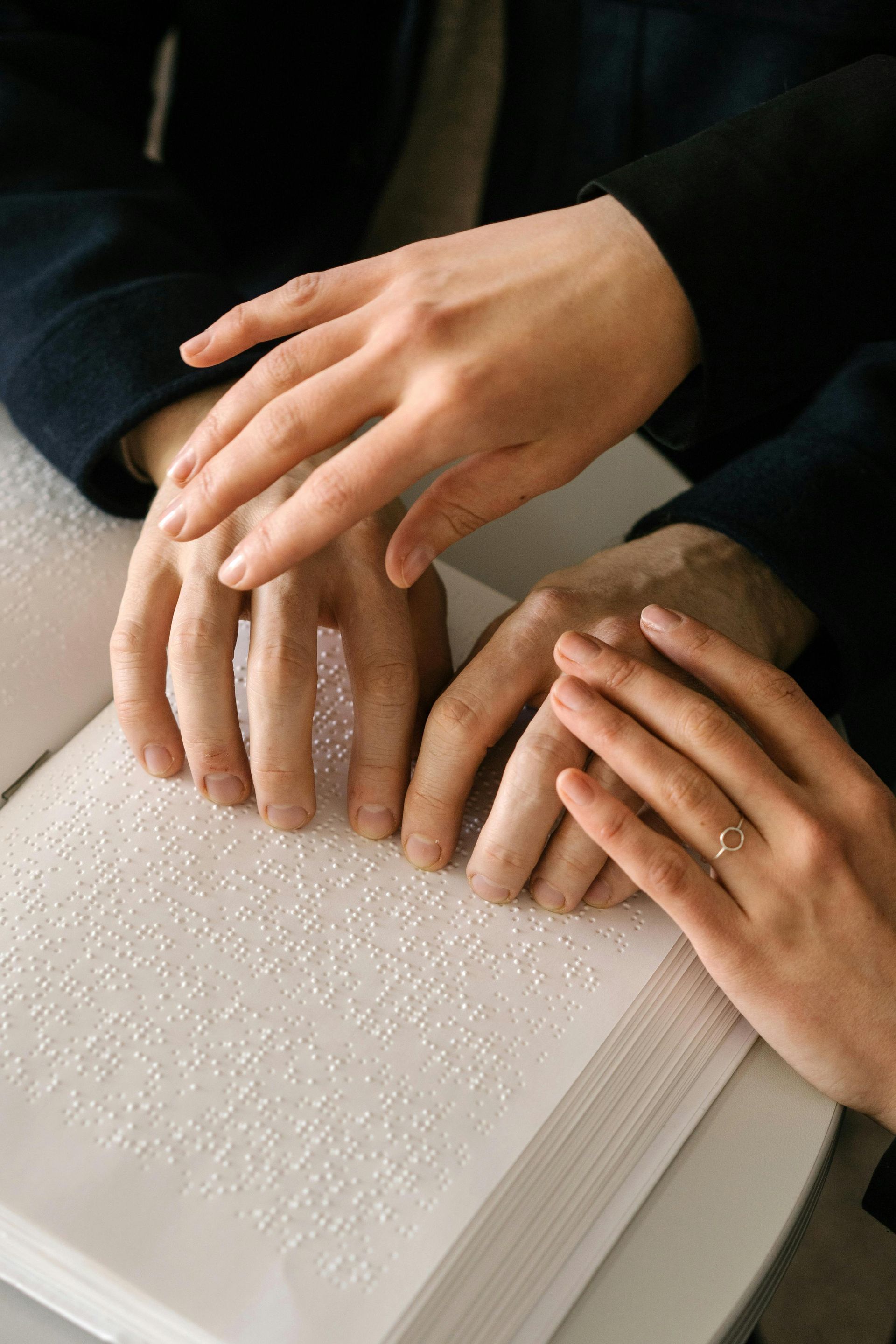 A man and a woman are reading a braille book together.