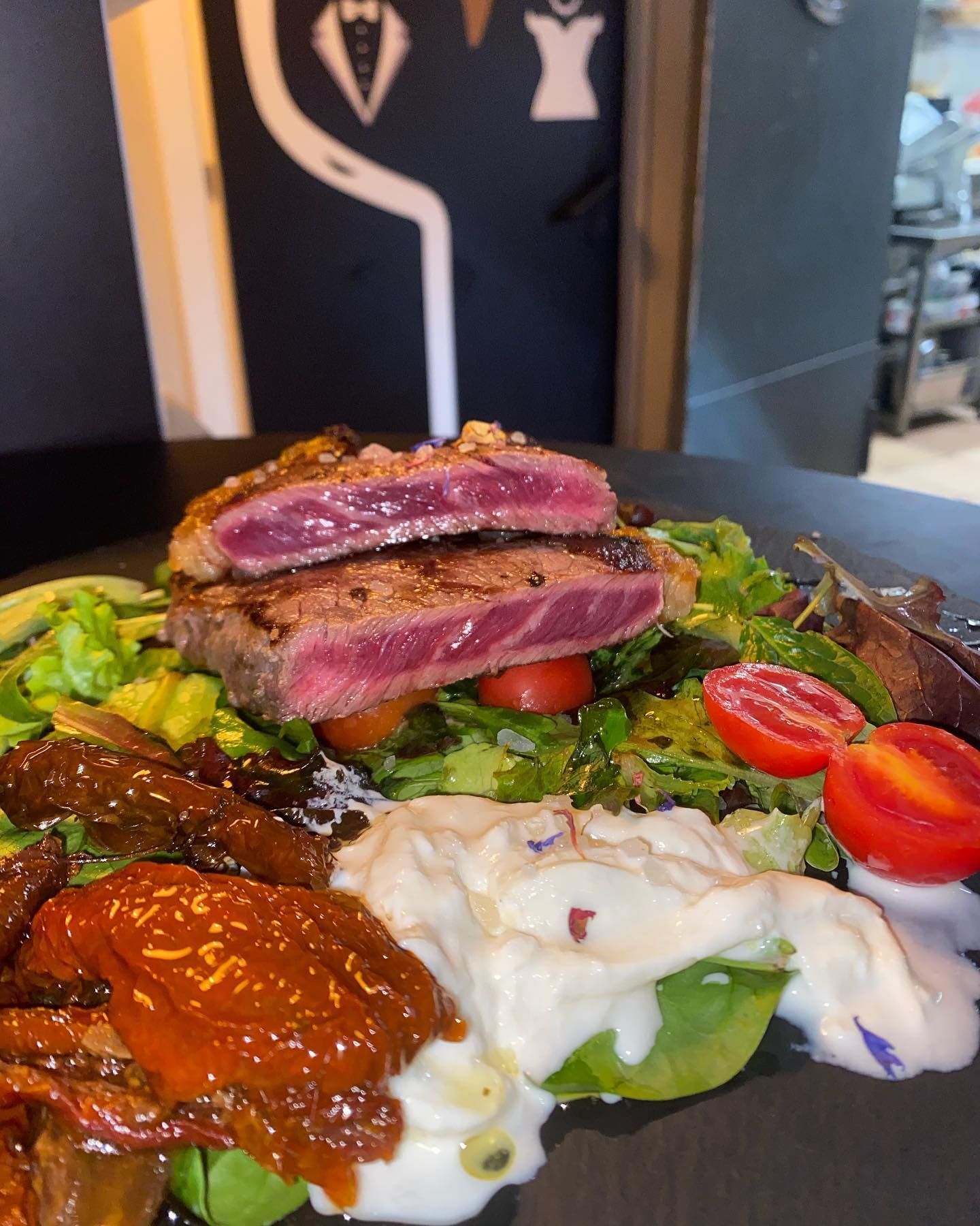 Insalata di bistecca con bistecca tagliata a fette e cotta al sangue, pomodori secchi, pomodori, verdure e salsa cremosa.