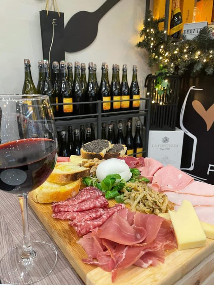 Un tagliere di salumi con bottiglie di vino, salame, prosciutto, formaggio, pane e champagne in un negozio.