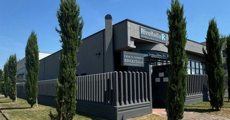 Un grande edificio con una recinzione attorno e alberi di fronte.