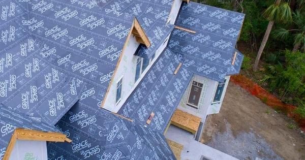 Two men are working on the roof of a house