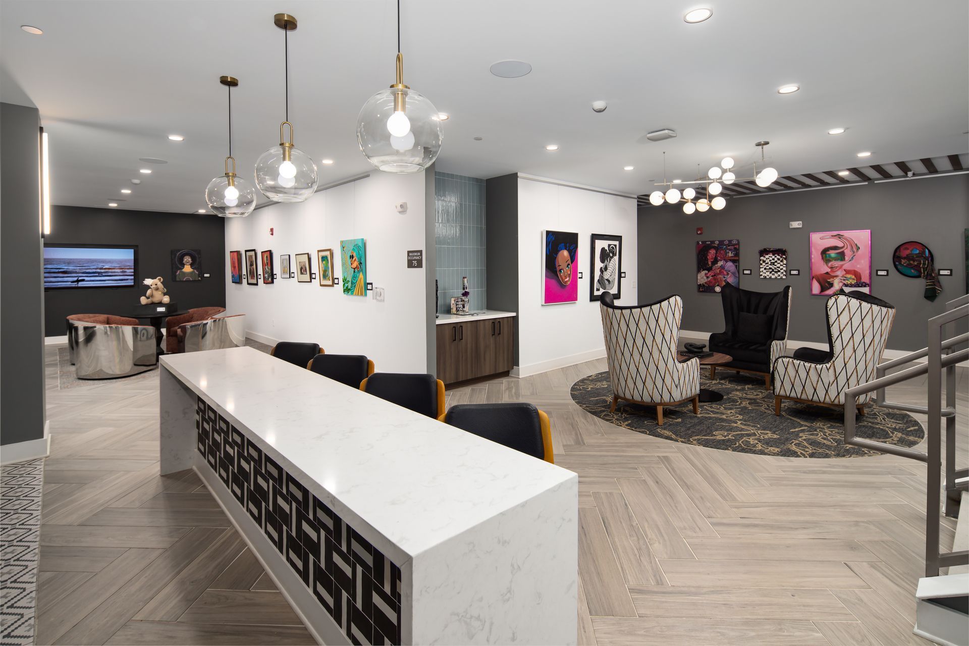 A modern lobby with a white marble bar, patterned chairs on a circular rug, and art displayed on the walls.