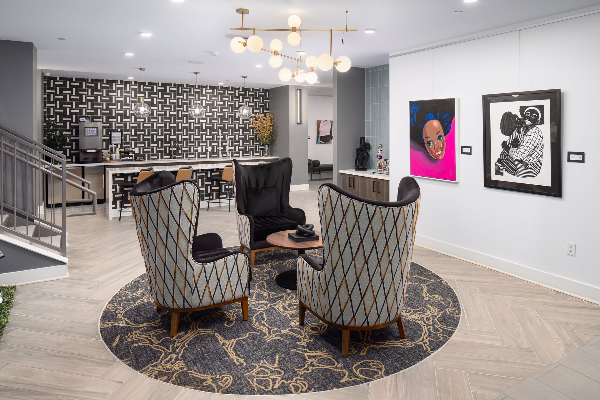 Modern lounge area with two patterned armchairs, a black wingback chair, and artwork on a white wall.