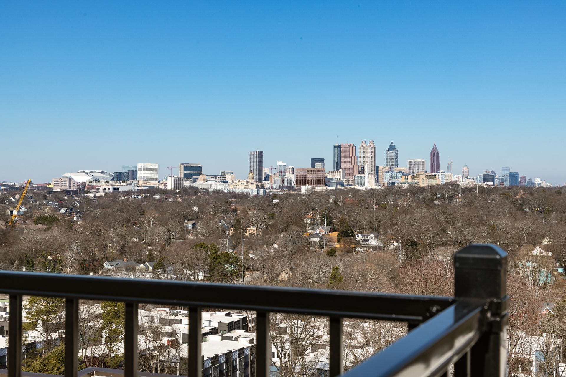 A panoramic view of the Atlanta skyline seen from a high balcony, featuring numerous skyscrapers over a tree-filled area.