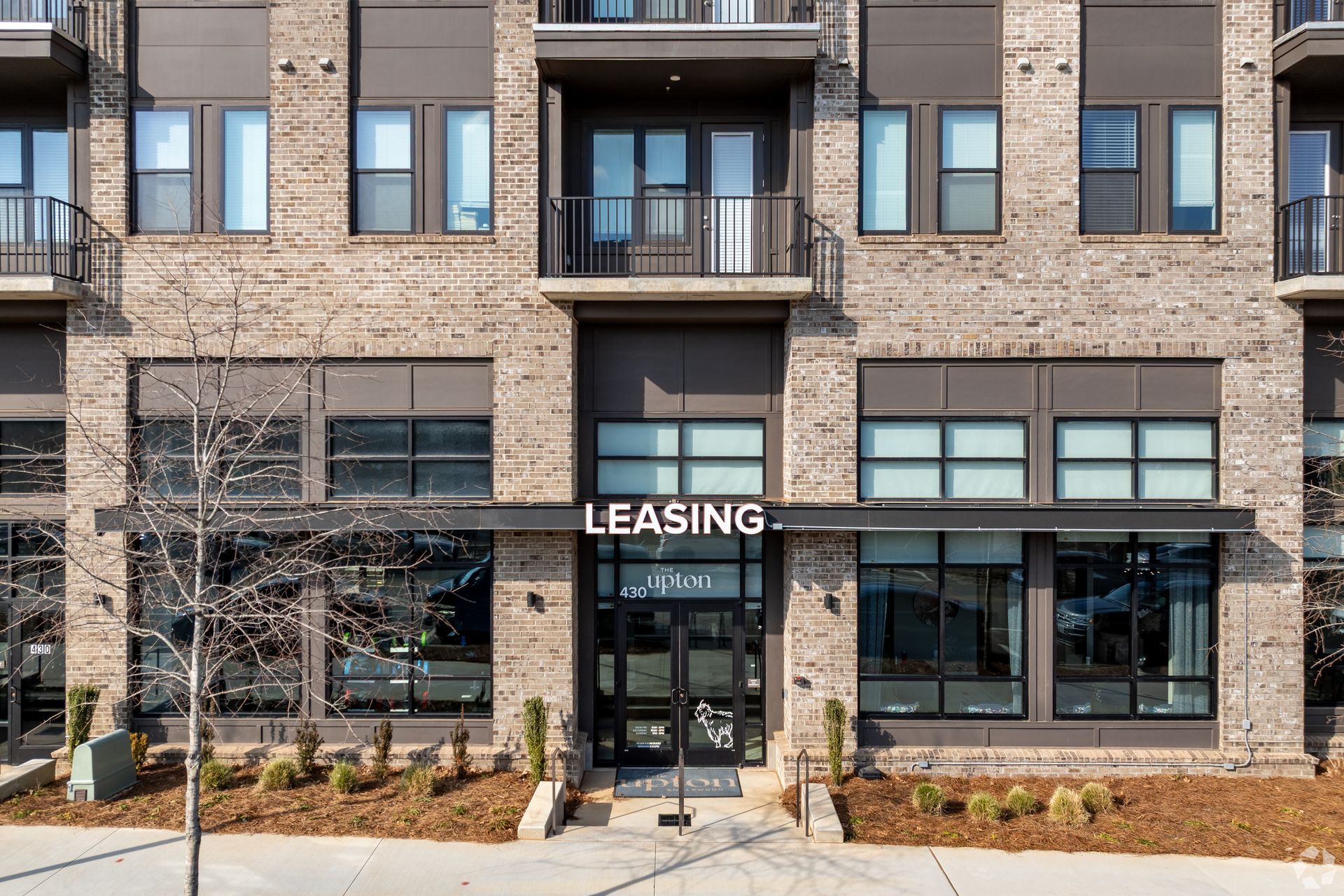 A brick apartment building exterior featuring a central glass-paned entrance with a 