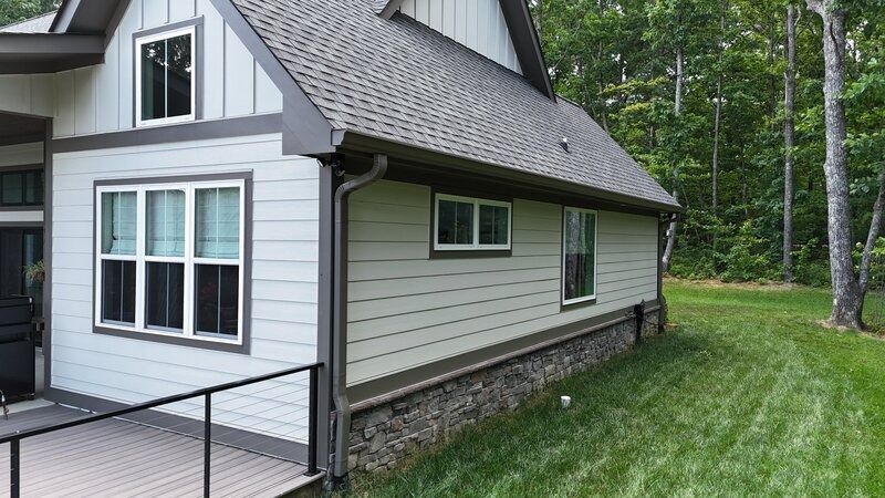 Light green house with dark trim, windows, and a grassy yard.