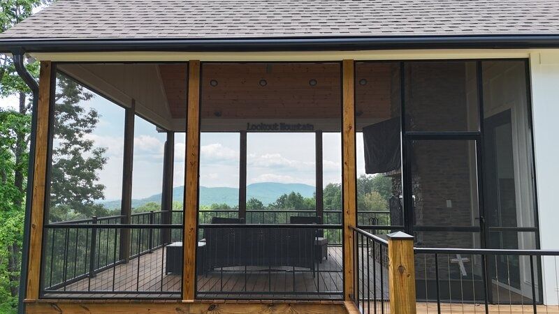 Screened-in porch with wood posts, black railing, and mountain view, with a television mounted on the wall.