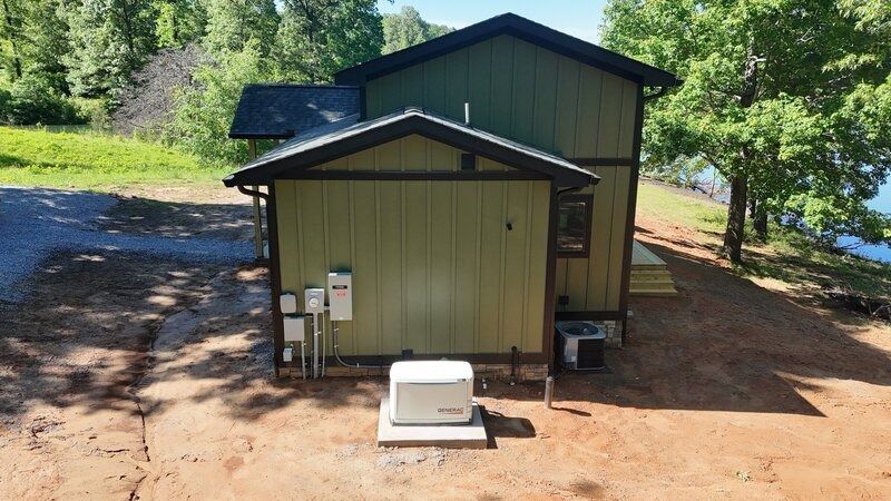 Green house with attached utility area; generator and electrical equipment in front.