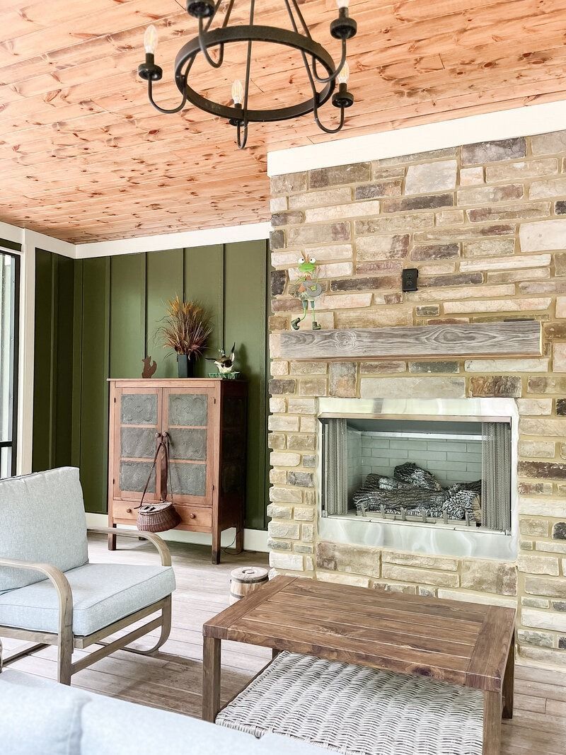 Cozy living area with stone fireplace, wood ceiling, green wall, and decorative furniture.