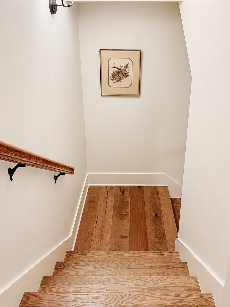 Wooden staircase with a white wall and a framed picture.