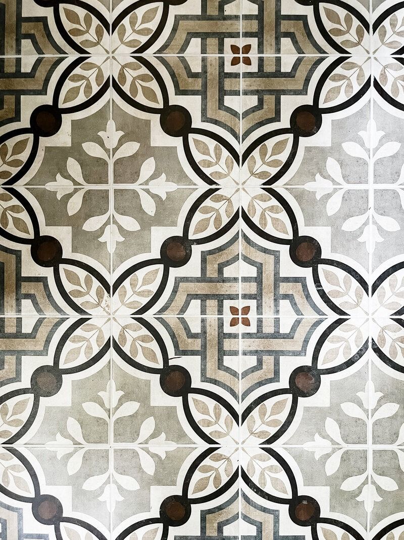Decorative tile floor pattern with gray, white, and brown geometric and floral designs.