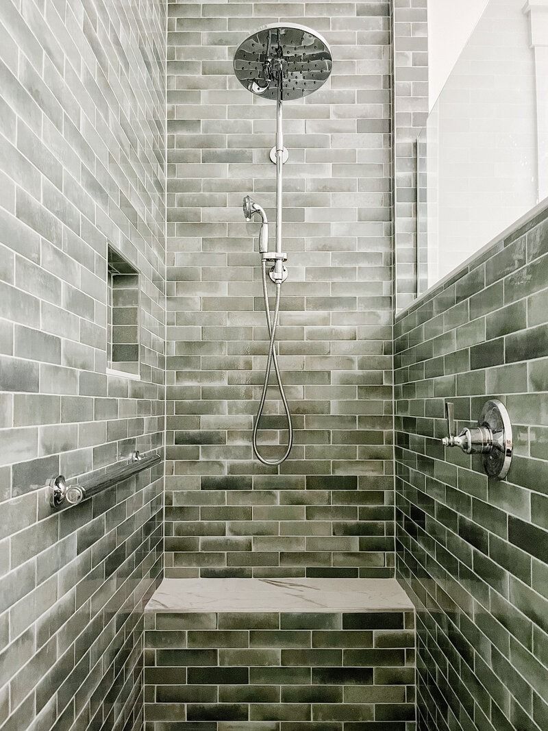 Shower with gray brick-like tiles, a circular showerhead, and a built-in bench.