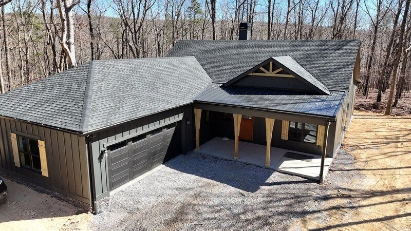 Dark gray modern home with a garage, porch, and a triangular architectural accent.