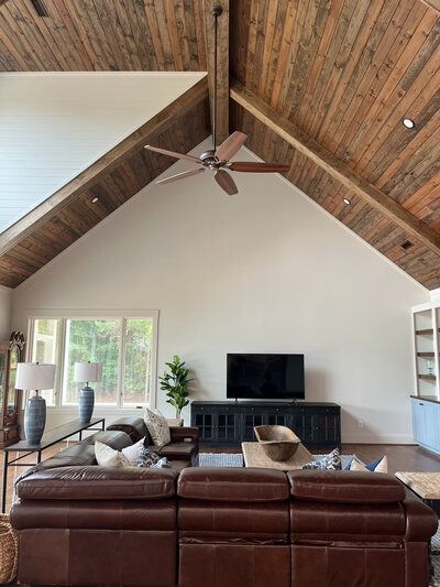Living room with brown leather sofa, TV, and wooden ceiling.
