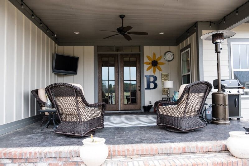 Covered patio with wicker chairs, TV, and outdoor heater.