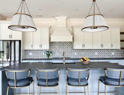 Kitchen with white cabinets, blue patterned backsplash, and gray island with four blue-cushioned barstools.