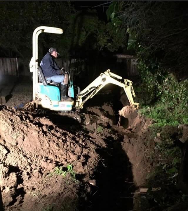 man using small excavator to dig trench for pipelines