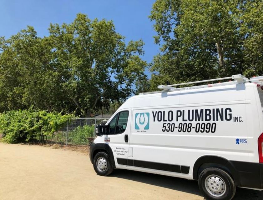 A white van from yolo plumbing inc. is parked in a parking lot.