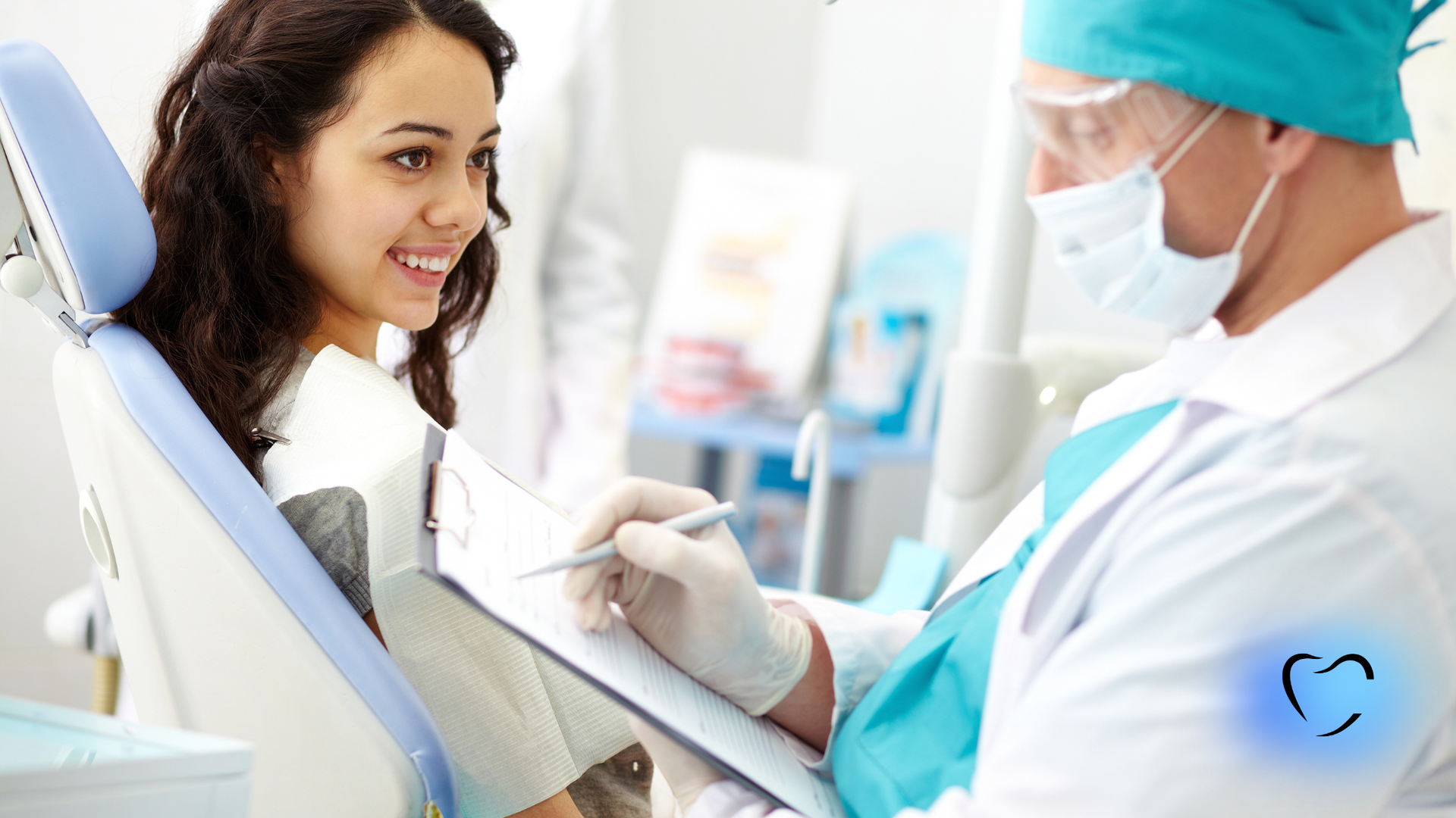 Woman in dentist chair, smiling, facing dentist writing on clipboard. Clinic setting.