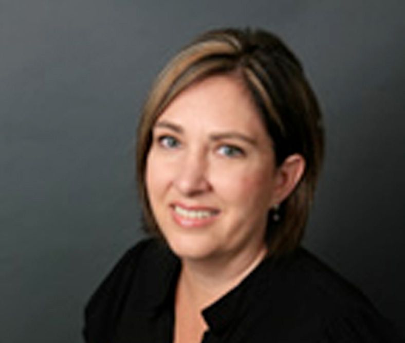 A woman in a black shirt is smiling for the camera.