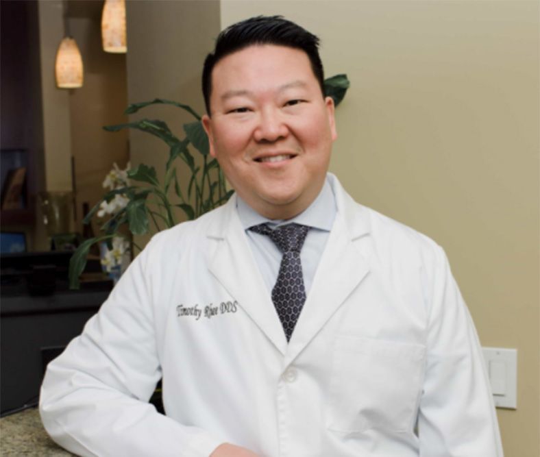 A man in a white coat and tie is smiling for the camera