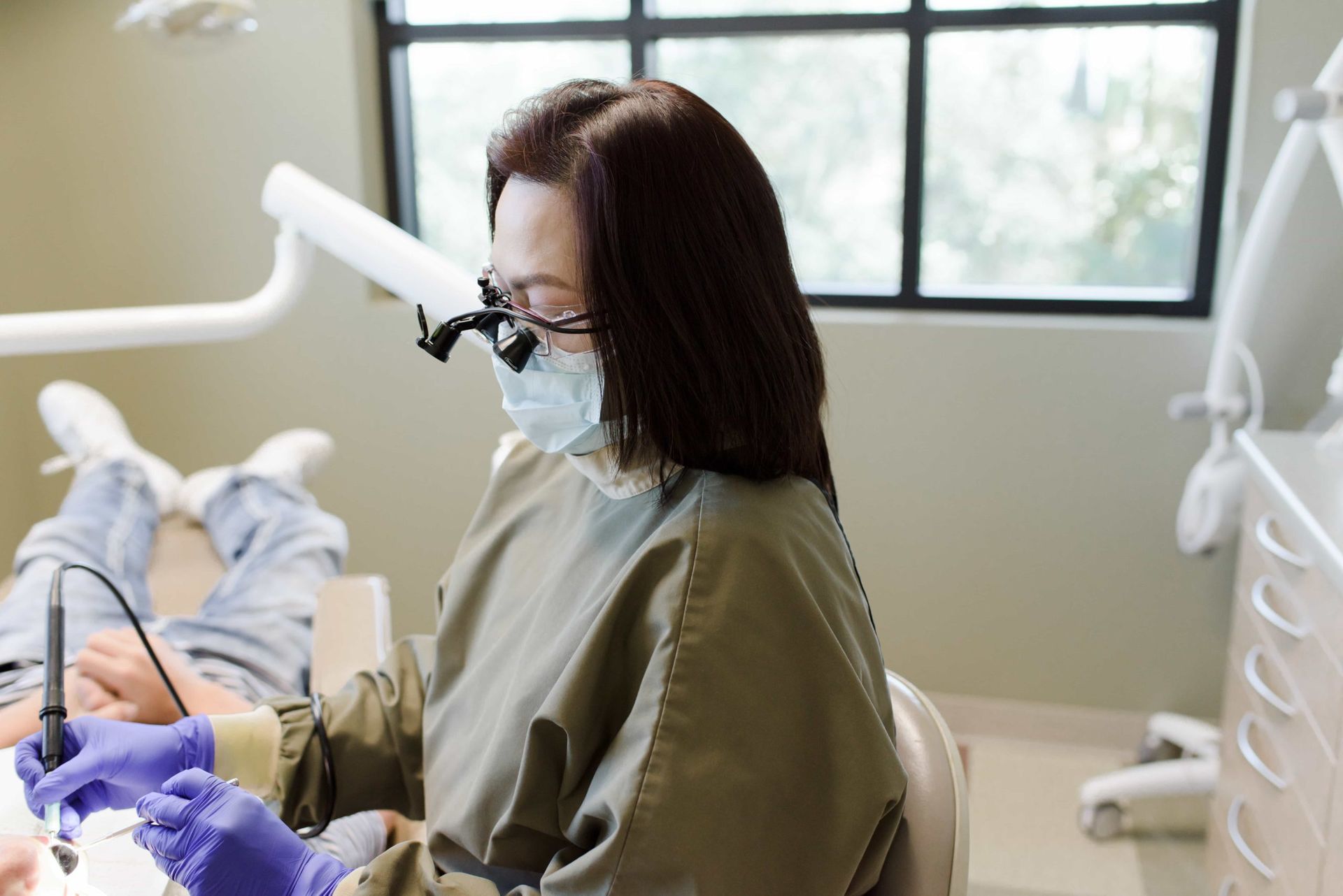 A female dentist is working on a patient 's teeth in a dental office.