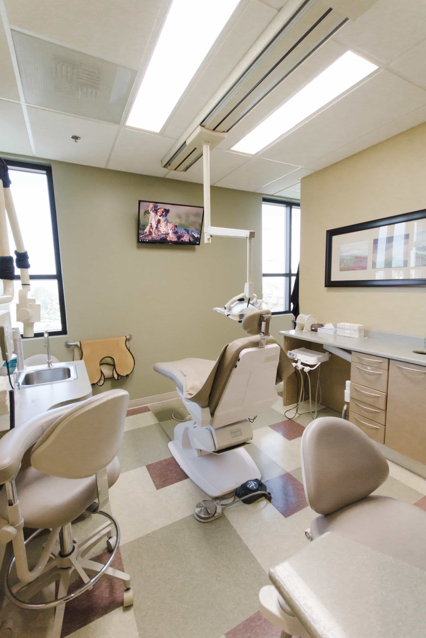 A dental office with a chair and a television on the wall