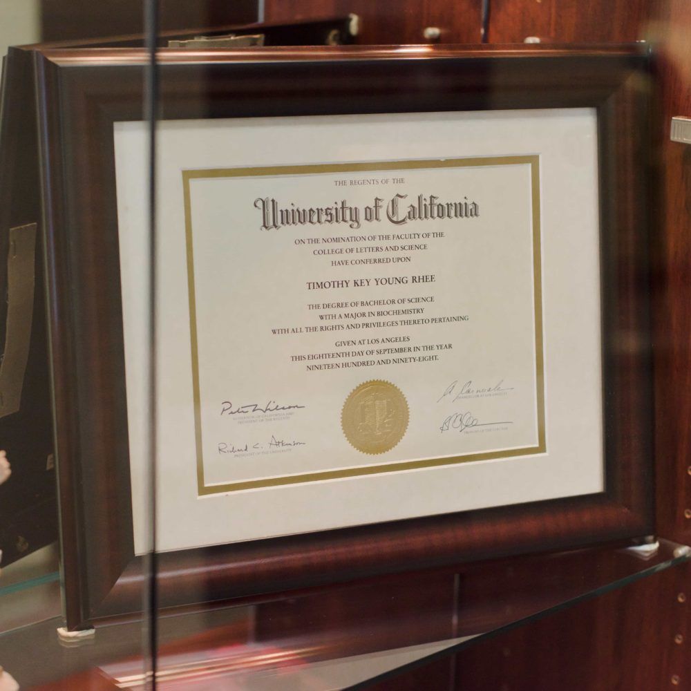 A university of california diploma is framed in a glass case