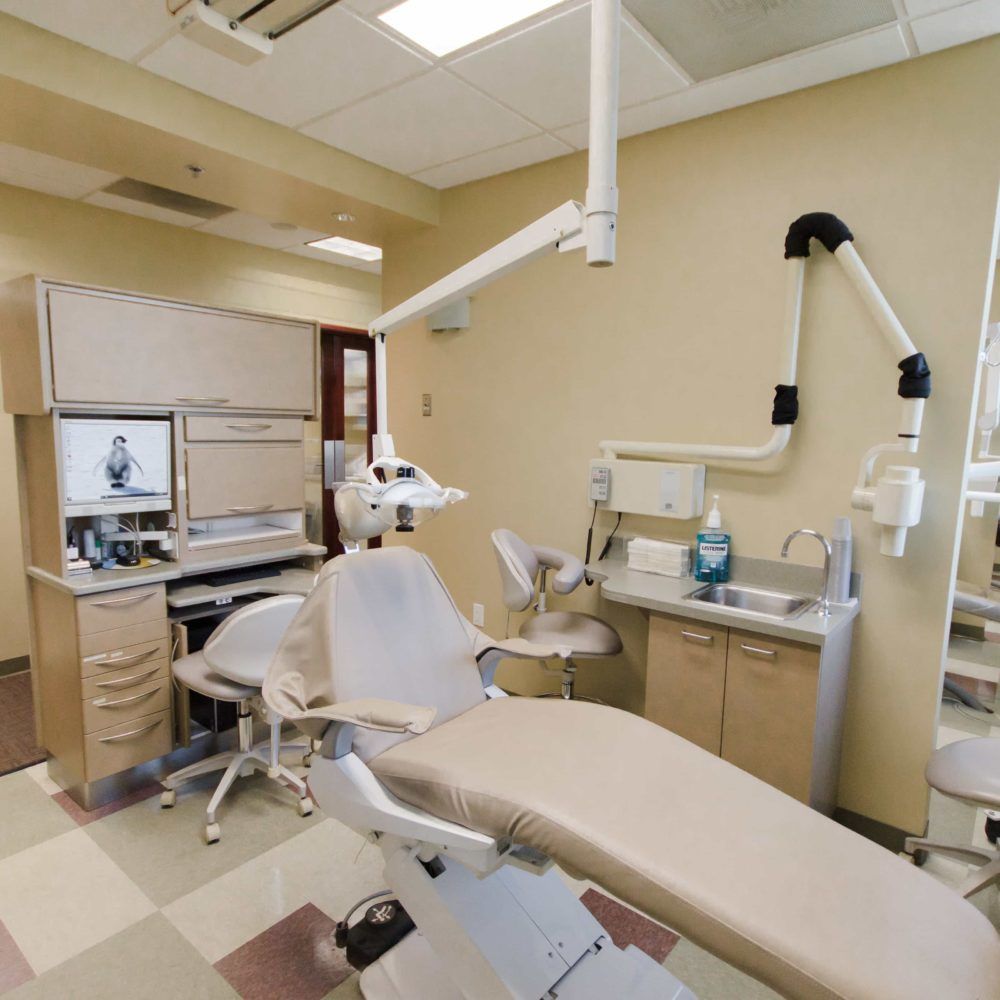 A dental office with a dental chair and a computer