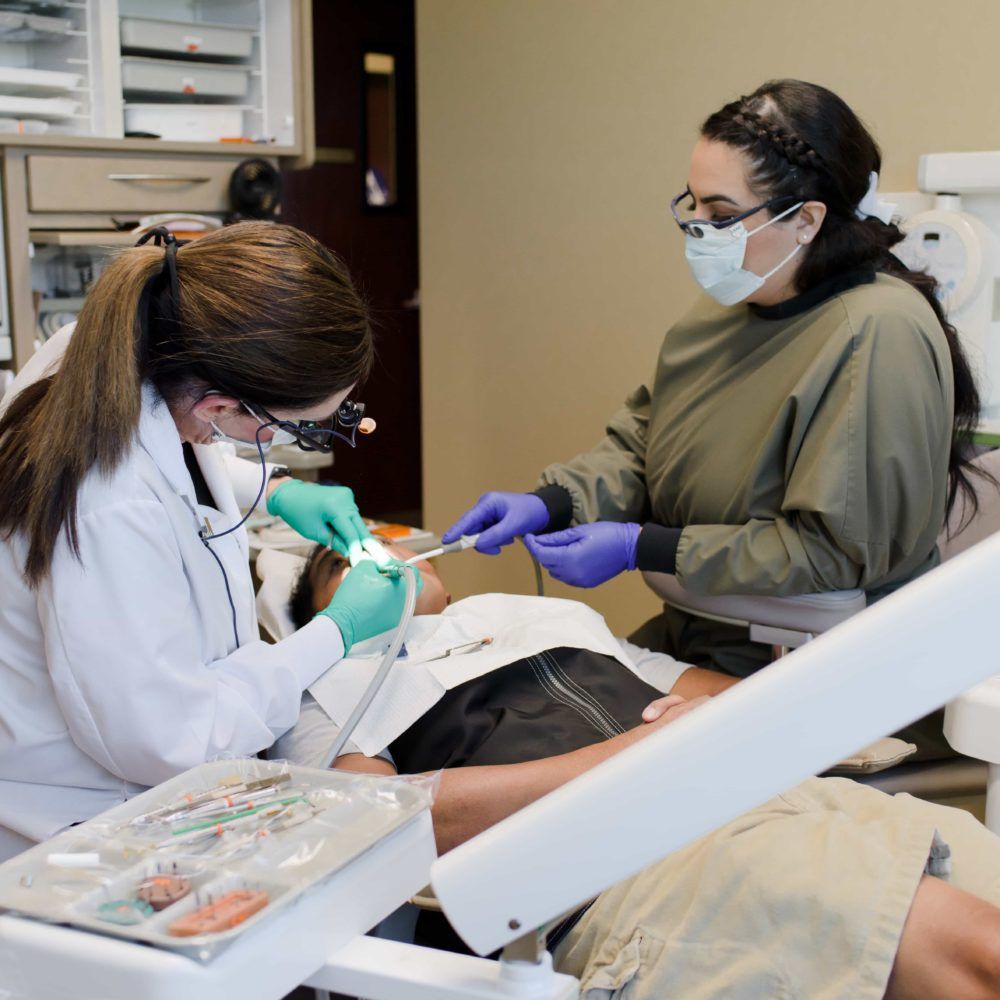 A dentist is examining a patient 's teeth in a dental office
