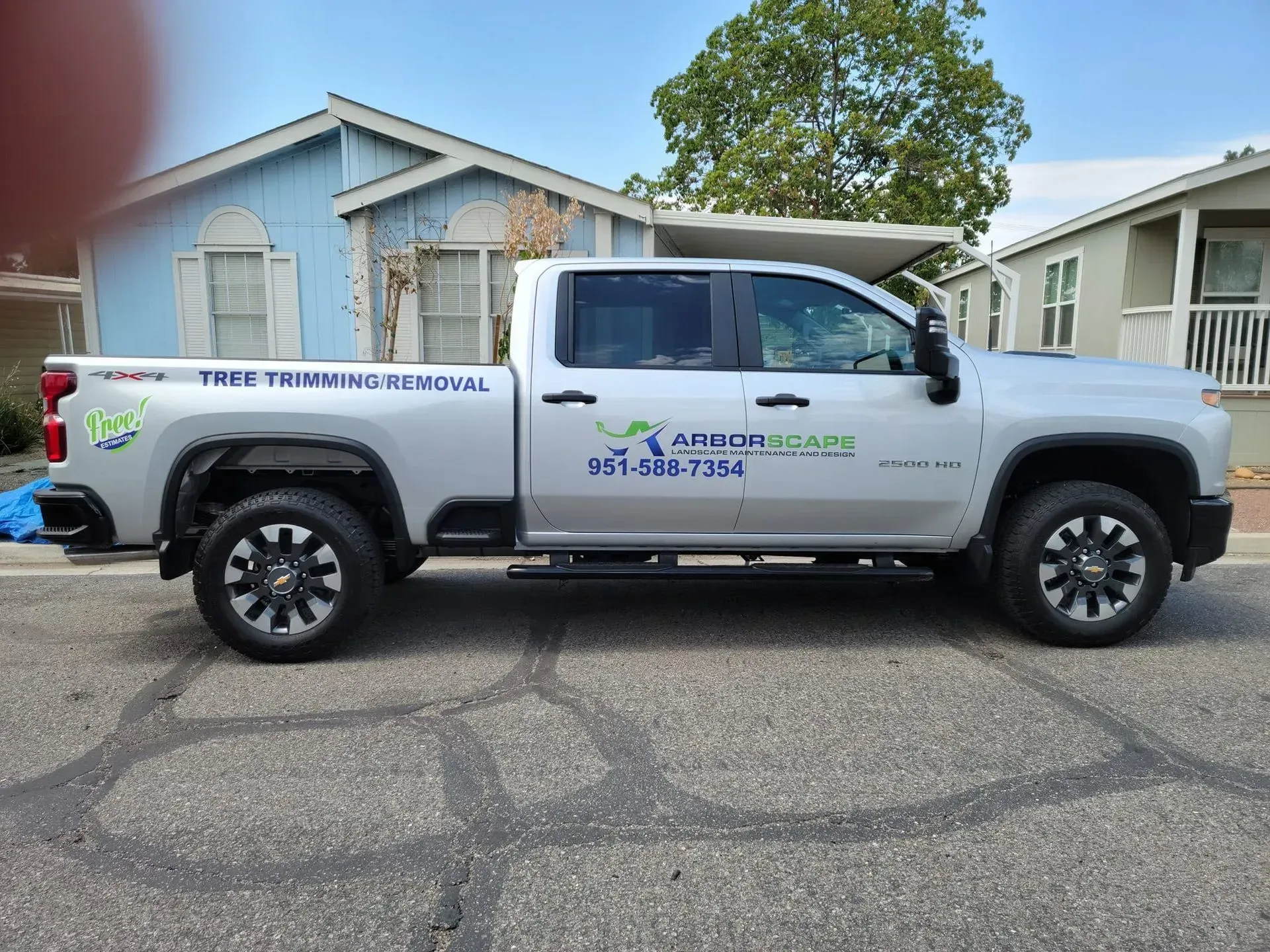 A white truck is parked in front of a blue house.
