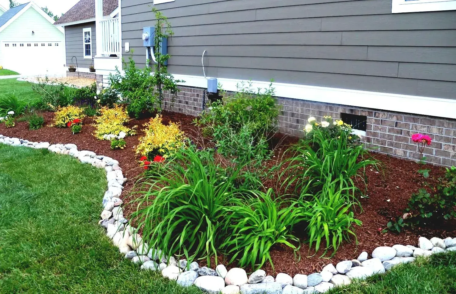 A garden with flowers and rocks in front of a house