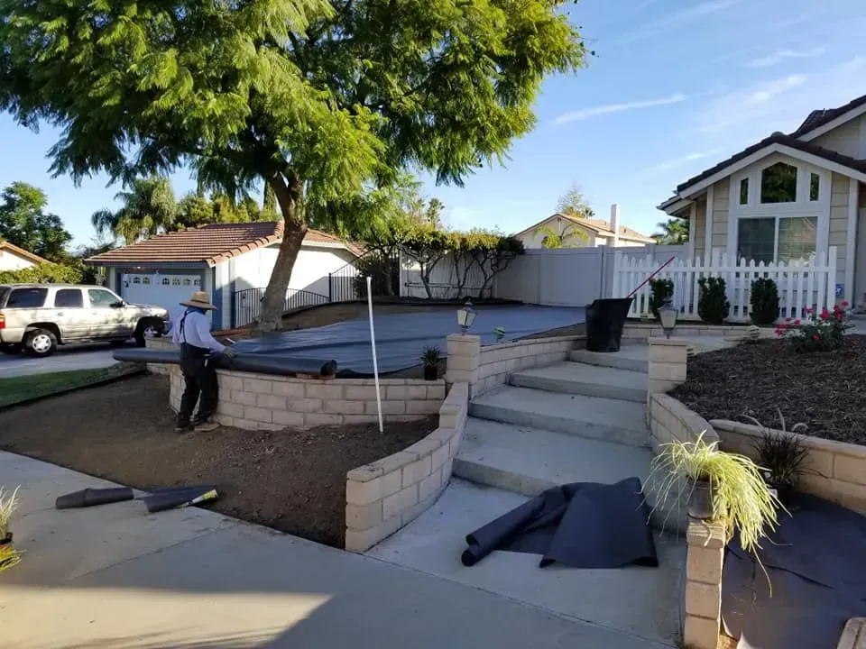 A man in a hat is standing in front of a house.
