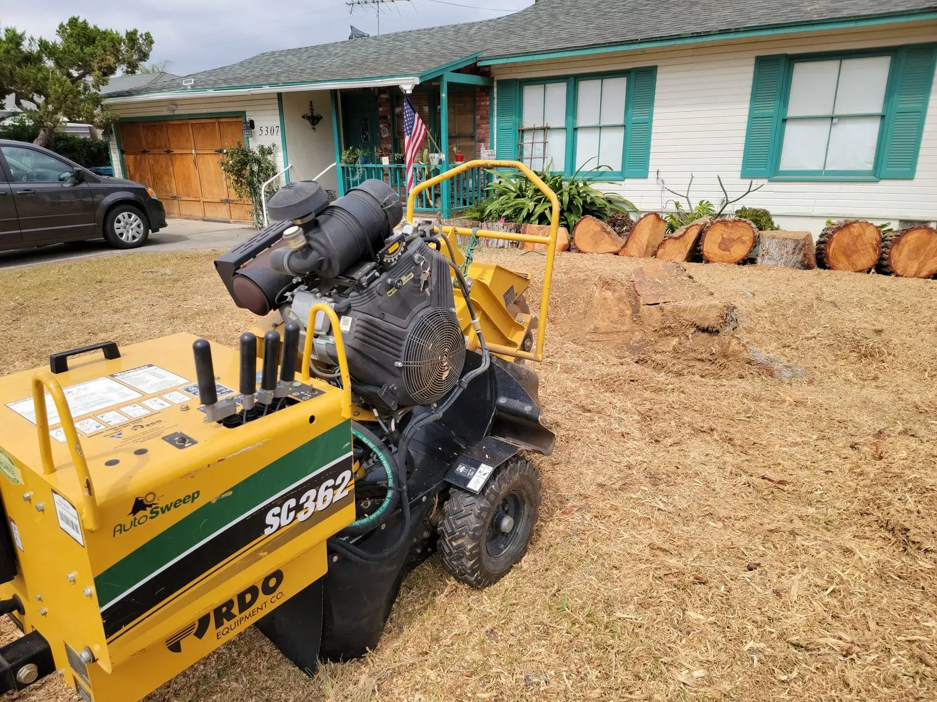 A yellow and green machine is sitting in front of a house.