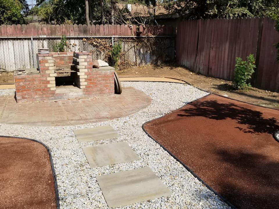 A backyard with a red fence and a brick fireplace