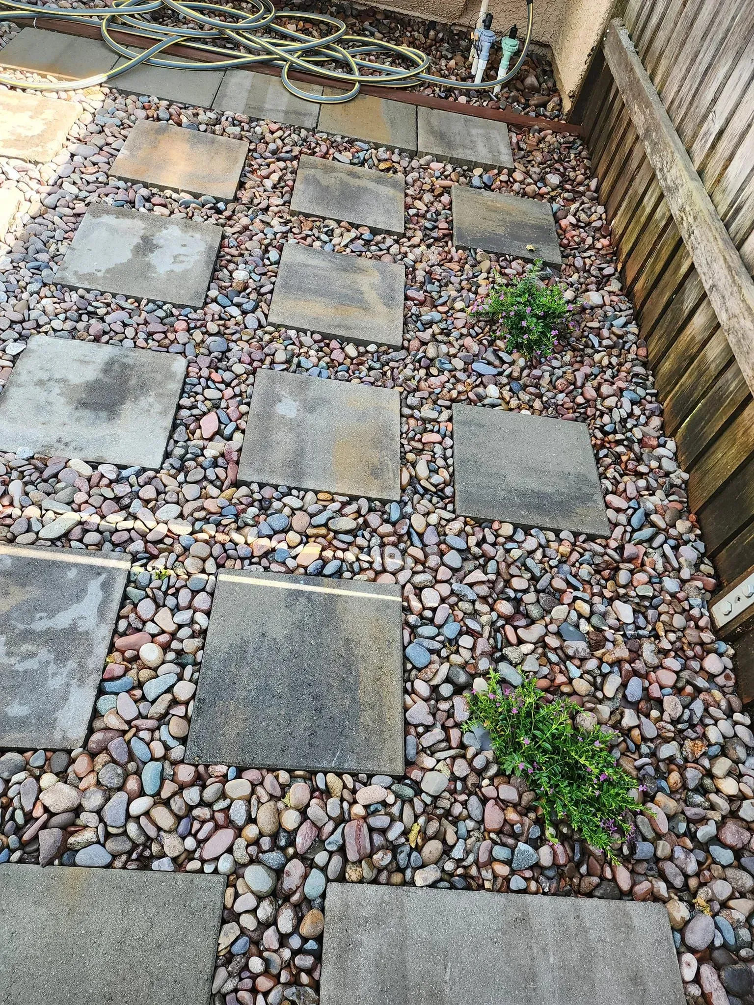 A stone walkway surrounded by rocks and a fence.