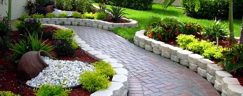 A brick walkway surrounded by plants and rocks in a garden.