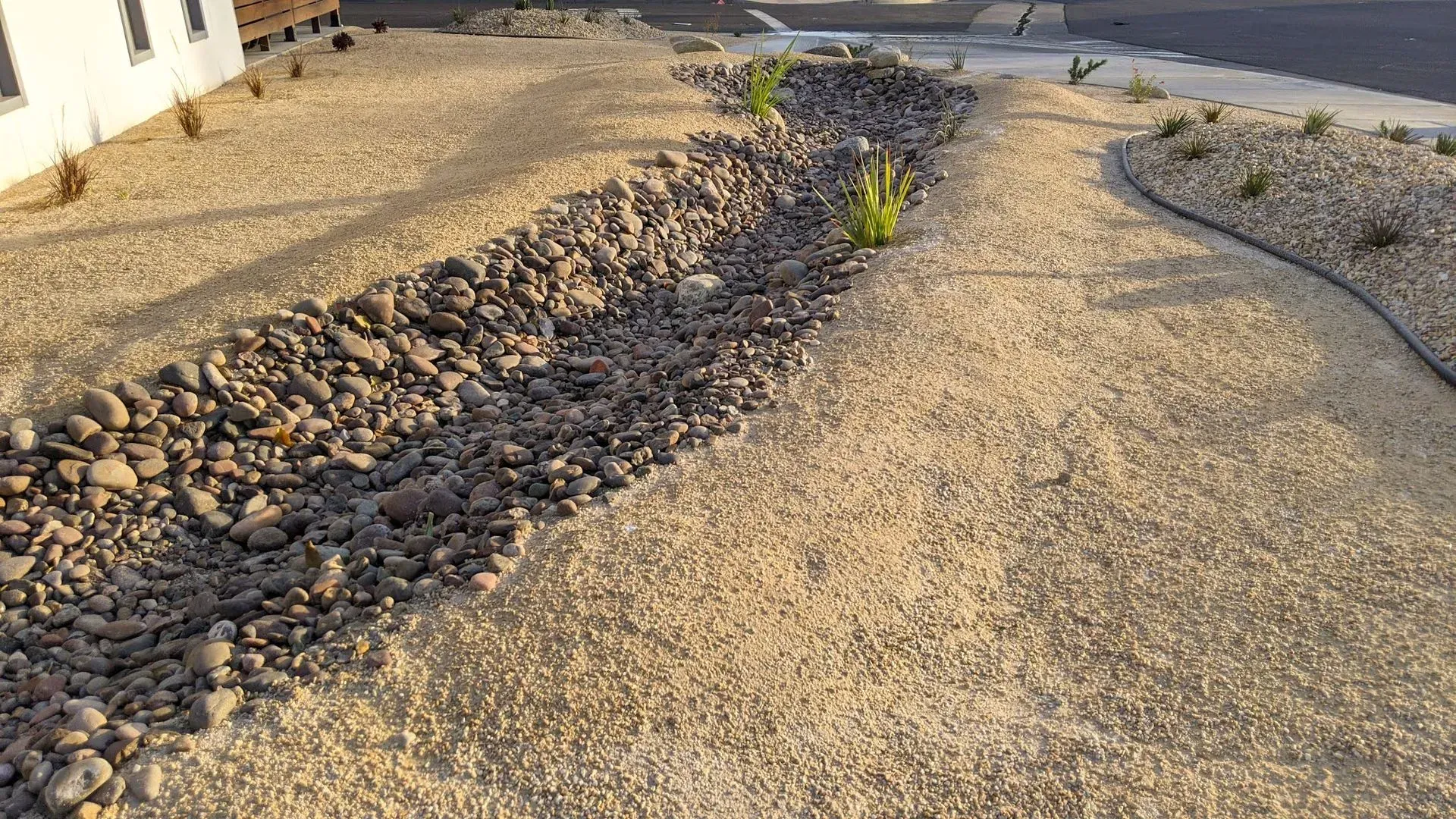 A hose is laying on the ground next to a pile of gravel.