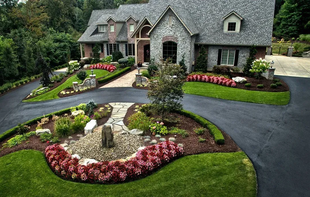 A large house with a large driveway and a lot of flowers in front of it.