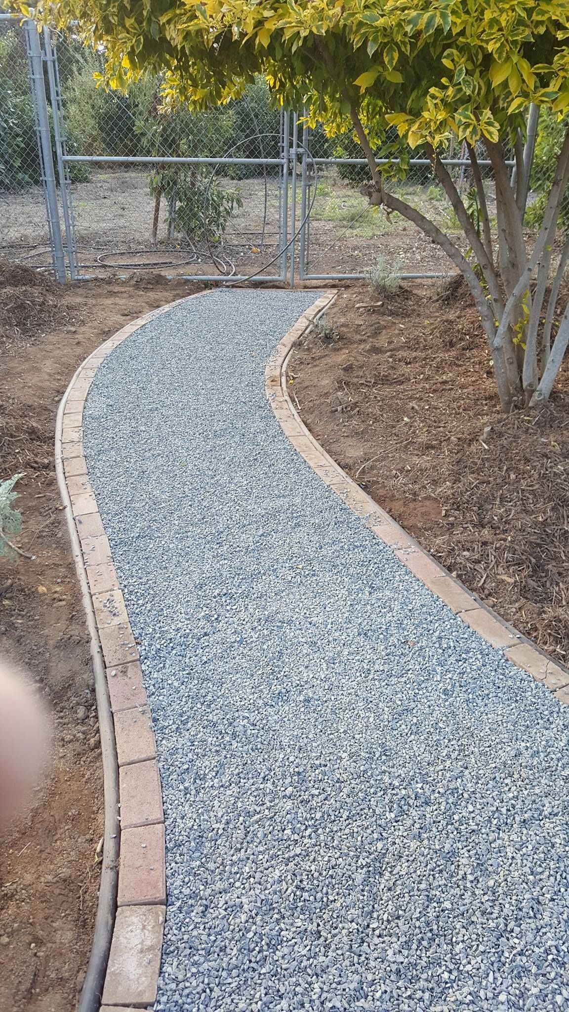 A walkway made of gravel and bricks in a garden.