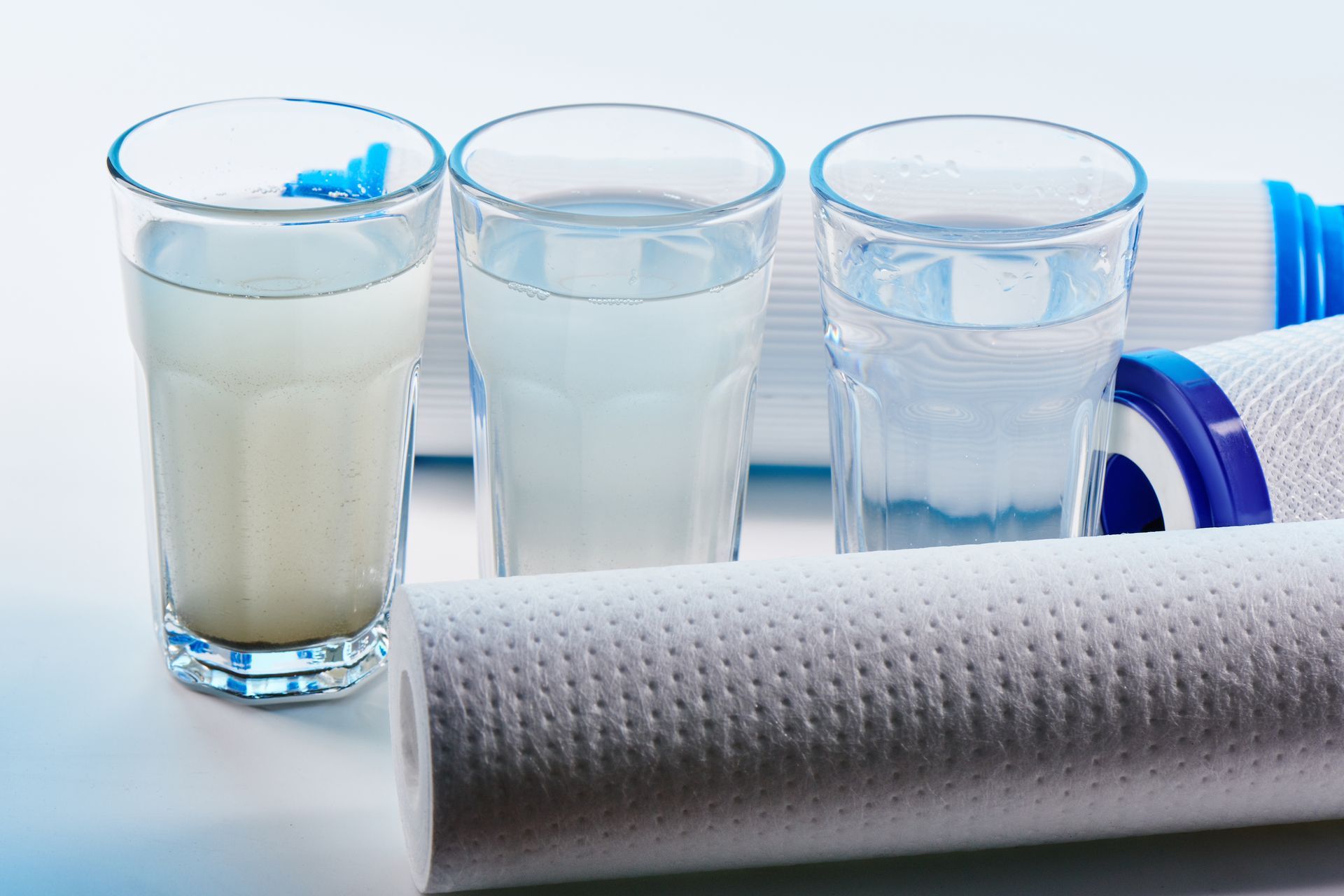 Three glasses of water showing filtration progression with filters. One is cloudy, the next lighter, and the last is clear.